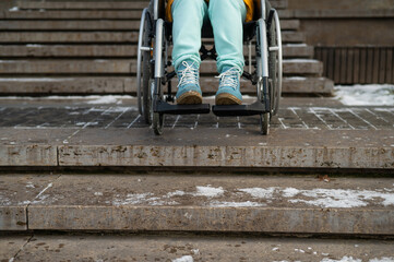 Woman in a wheelchair near the stairs in the park in winter.
