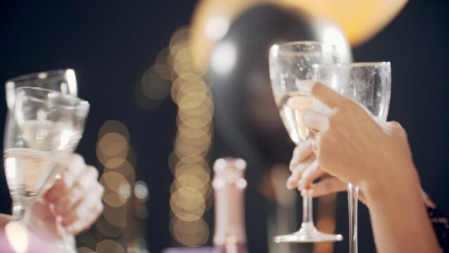 Women congratulating friends, smiling, laughing, blowing whistle, clinking glasse of champagne and drinking wine. Portraits of young multiracial girls sitting at festive table and celebrating holiday.