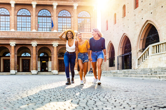 Fototapeta Happy multiracial women having fun together on summer vacation - Female friends hugging each other while walking in italian city street - Friendship and happy lifestyle