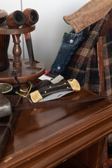 Fototapeta na wymiar Pocket folding knife lying on table with compass in front of denim work coat