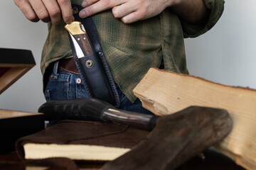 Pocket knife in sheath on belt of man wearing plaid shirt 