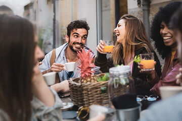 Black and white cheerful mates laughing enjoying meal having fun sitting together at restaurant table - Food and beverage lifestyle concept on young people enjoying time together outside at cafe