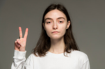 close-up portrait of a young Ukrainian girl who shows the number with her hands on a gray background