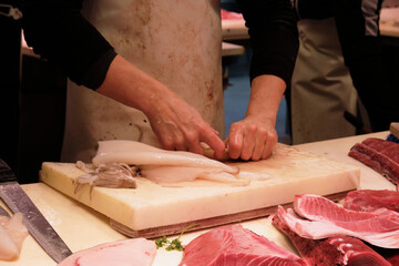 A man in an apron cuts squid and butchers fish at the fish market. Spanish fish market, a man cuts...