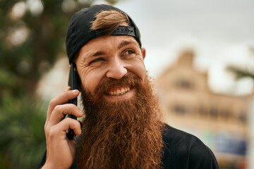 Young irish hipster man smiling happy talking on the smartphone at the city.