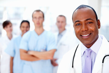 Confident doctor with medical team in background. Focus on doctor with colleagues in background.
