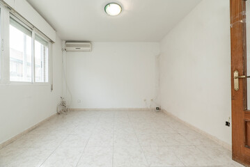 Empty living room with light glossy stoneware floor, large aluminum window, wooden door, ceiling light fixture and air conditioning