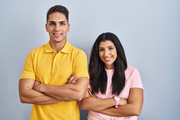 Obraz premium Young couple standing over isolated background happy face smiling with crossed arms looking at the camera. positive person.