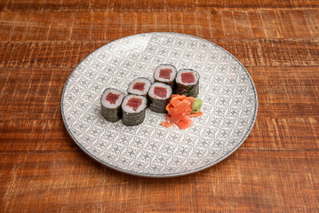 Six-piece portion of red tuna maki wrapped in nori seaweed and Japanese rice cooked with wasabi and ginger on a nice plate