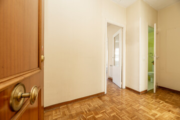 Entrance door and distributor hall of a residential house with entrance to a furnished living room, toilet and oak parquet floors