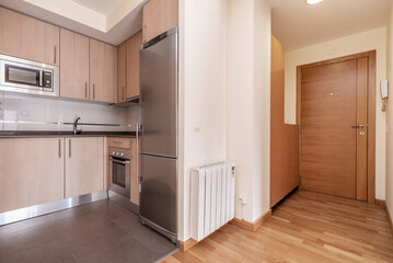 open kitchen equipped with wood colored cabinets, gray stone countertop and stainless steel appliances in a studio rental with oak parquet flooring