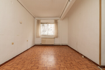 empty room with wooden floors similar to sintasol, aluminum window with bars and white curtains and white aluminum radiators