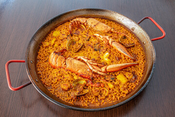 Spanish lobster paella with shellfish, mussels, prawns, cuttlefish and a delicious sauce on its paella pan
