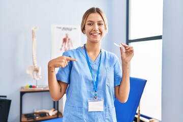 Young blonde woman holding plastic aligner for bruxism pointing finger to one self smiling happy and proud