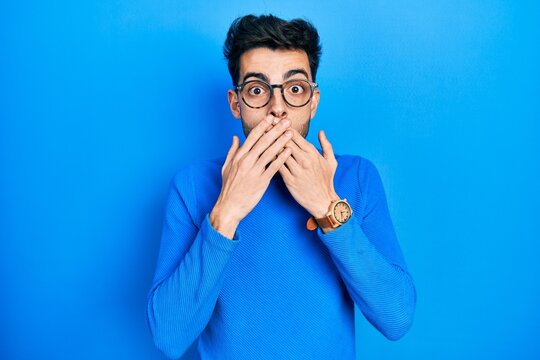 Young hispanic man wearing casual clothes and glasses shocked covering mouth with hands for mistake. secret concept.
