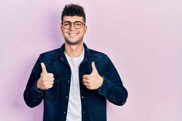 Young hispanic man wearing casual clothes and glasses success sign doing positive gesture with...