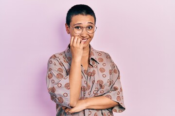 Beautiful hispanic woman with short hair wearing glasses looking stressed and nervous with hands on...