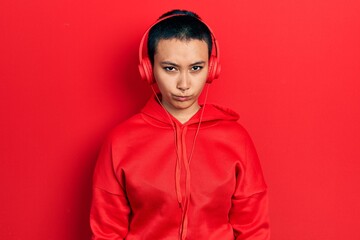 Beautiful hispanic woman with short hair listening to music using headphones skeptic and nervous, frowning upset because of problem. negative person.