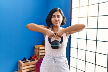 Fototapeta na wymiar Young latin woman smiling confident training using kettlebell at sport center