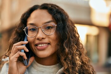 Young latin woman smiling happy talking on the smartphone at the city.