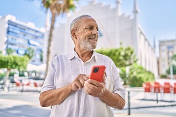 Senior man smiling confident using smartphone at street