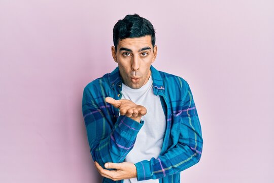 Handsome hispanic man wearing casual clothes looking at the camera blowing a kiss with hand on air being lovely and sexy. love expression.