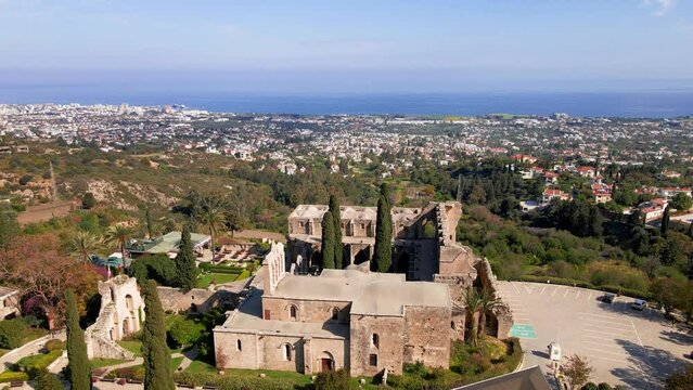 Aerial 4K view of beautiful Bellapais Village with Bellapais Monastery in Kyrenia, North Cyprus surrounded with an amazing green Mediterranean nature and picturesque landscapes in Cyprus.