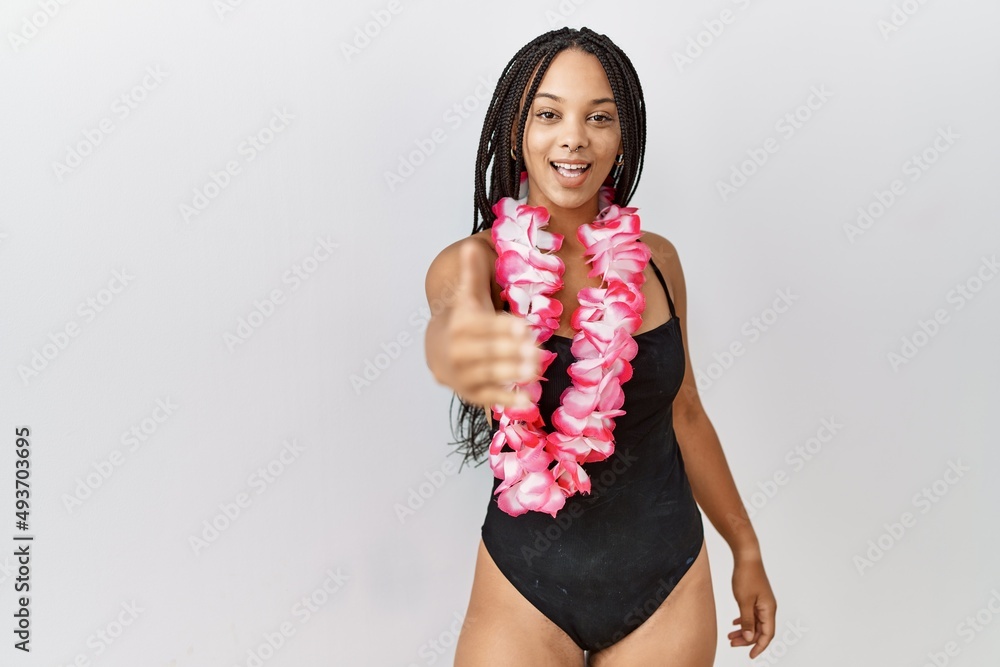 Sticker young african american woman wearing swimsuit and hawaiian lei smiling friendly offering handshake a