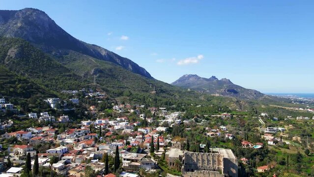 Aerial 4K view of beautiful Bellapais Village with Bellapais Monastery in Kyrenia, North Cyprus surrounded with an amazing green Mediterranean nature and picturesque landscapes in Cyprus.