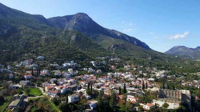Aerial 4K view of beautiful Bellapais Village with Bellapais Monastery in Kyrenia, North Cyprus surrounded with an amazing green Mediterranean nature and picturesque landscapes in Cyprus.