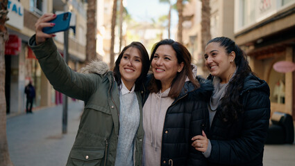 Mother and daugthers making selfie by the smartphone standing together at street