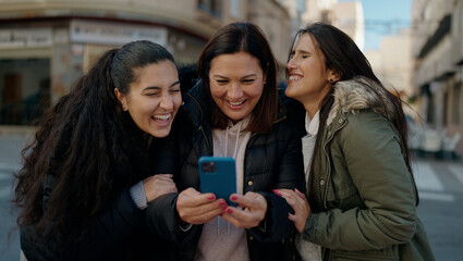 Mother and daugthers using smartphone standing together at street
