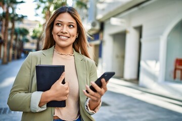 Young latin woman smiling confident using smartphone at street