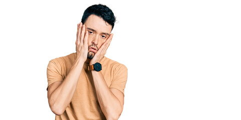 Hispanic man with beard wearing casual t shirt tired hands covering face, depression and sadness, upset and irritated for problem