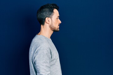 Young hispanic man wearing casual clothes looking to side, relax profile pose with natural face with confident smile.