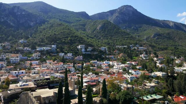Aerial 4K view of beautiful Bellapais Village with Bellapais Monastery in Kyrenia, North Cyprus surrounded with an amazing green Mediterranean nature and picturesque landscapes in Cyprus.