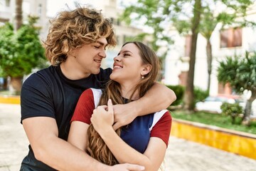 Fototapeta premium Young caucasian couple smiling happy and hugging at the city.