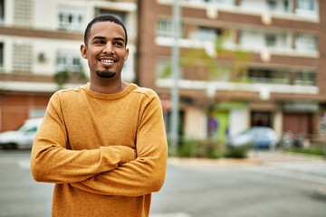 Fototapeta premium Young african american man smiling happy with arms crossed gesture at the city.