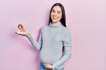 Beautiful woman with blue eyes expecting a baby, holding anatomic fetus looking positive and happy...