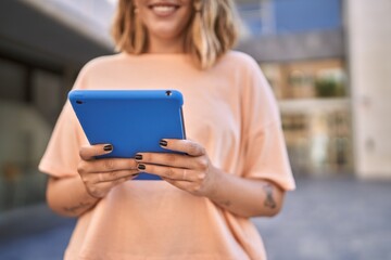 Young hispanic woman smiling confident using touchpad at street