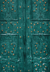 An old dark emerald green metal door with an openwork ornament. Vintage background closeup. Medieval forging technologies.