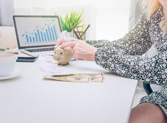 businesswoman in a gray dress holds a piggy bank in her hands while sitting on a chair. Business concept