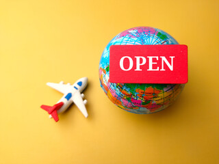 Top view airplane and earth globe with text OPEN on yellow background.