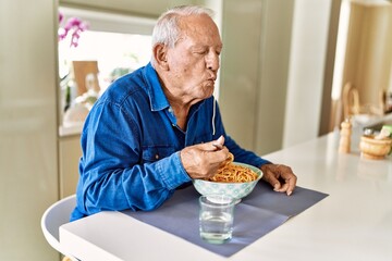 Senior man eating spaghetti at kitchen