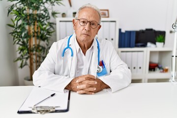 Senior man wearing doctor uniform working at clinic