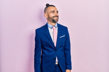 Young hispanic man wearing business suit and tie looking away to side with smile on face, natural expression. laughing confident.