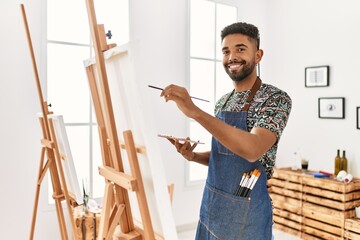 Young african american artist man smiling happy painting at art studio.