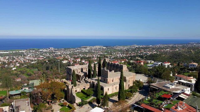 Aerial 4K view of beautiful Bellapais Village with Bellapais Monastery in Kyrenia, North Cyprus surrounded with an amazing green Mediterranean nature and picturesque landscapes in Cyprus.