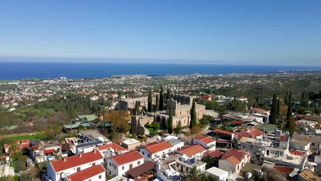Aerial 4K view of beautiful Bellapais Village with Bellapais Monastery in Kyrenia, North Cyprus surrounded with an amazing green Mediterranean nature and picturesque landscapes in Cyprus.