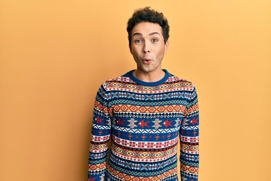 Young handsome man wearing casual winter sweater scared and amazed with open mouth for surprise, disbelief face